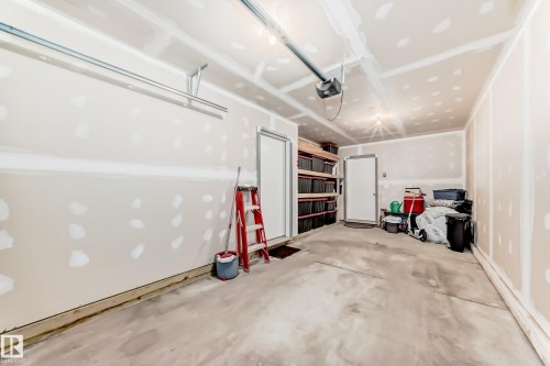 Spacious garage with concrete flooring, exposed drywall, overhead lighting, and two entry doors - 115 401 Southfork Drive, Leduc, AB - Indoor Photo Showing Garage