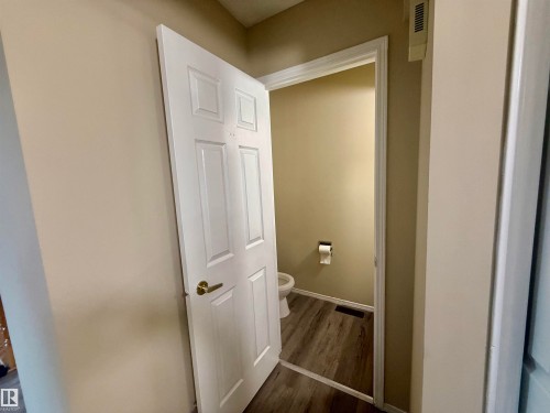 Interior half-bath featuring a white toilet, wood-finish flooring, and light-toned wall paint - 10905 74 Avenue, Edmonton, AB - Indoor Photo Showing Other Room