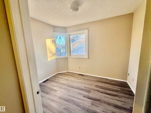 Room featuring wood-finish flooring, two large windows, neutral wall paint, and white trim - 10905 74 Avenue, Edmonton, AB - Indoor Photo Showing Other Room
