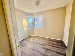 Room featuring wood-finish flooring, two large windows, neutral wall paint, and white trim - 