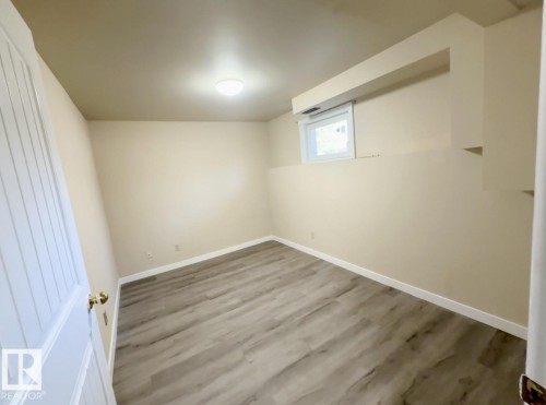 Interior room featuring wood-finish flooring, light-toned walls, and a single window - 10905 74 Avenue, Edmonton, AB - Indoor Photo Showing Other Room