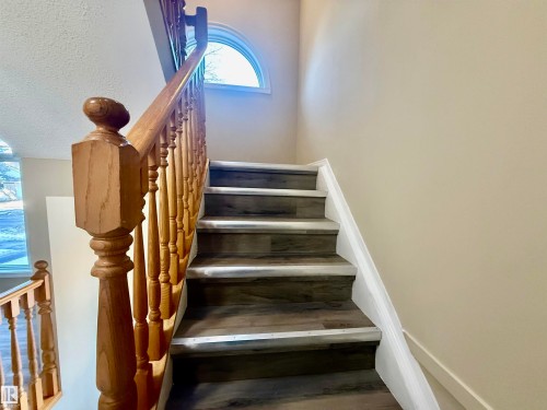 Staircase featuring wood-finish treads, light wood balusters, and a half-round window - 10905 74 Avenue, Edmonton, AB - Indoor Photo Showing Other Room