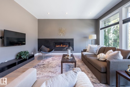 Spacious living area featuring a linear fireplace with dark stone surround, tall windows, recessed lighting, and light wood-finish flooring - 4204 Aspen Drive E, Edmonton, AB - Indoor Photo Showing Living Room With Fireplace