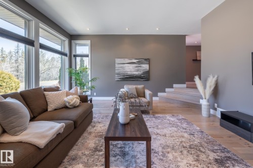 Living area featuring expansive windows, recessed lighting, wood-finish flooring, a contemporary accent wall, and a built-in media console - 4204 Aspen Drive E, Edmonton, AB - Indoor Photo Showing Living Room