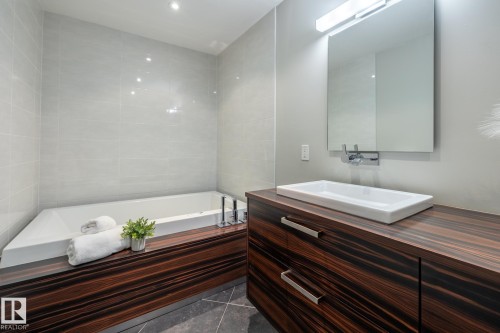 Modern bathroom featuring a built-in tub with tile surround, a vessel sink, and a wall-mounted faucet - 4204 Aspen Drive E, Edmonton, AB - Indoor Photo Showing Bathroom