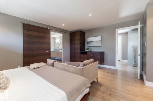 Bedroom featuring wood-finish flooring, a wood-finish barn door, built-in wood-finish cabinetry, recessed lighting, and a doorway to an additional interior space - 4204 Aspen Drive E, Edmonton, AB - Indoor Photo Showing Bedroom
