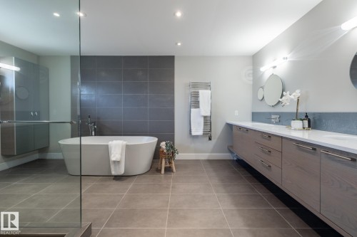 Spacious bathroom featuring a freestanding soaking tub with a tiled accent wall, a glass-enclosed shower, and a floating double vanity with integrated sinks - 4204 Aspen Drive E, Edmonton, AB - Indoor Photo Showing Bathroom