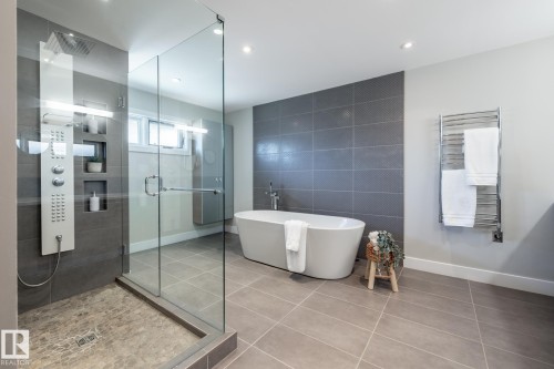 Spacious bathroom featuring a freestanding soaking tub, a frameless glass shower enclosure, and a multi-function shower panel - 4204 Aspen Drive E, Edmonton, AB - Indoor Photo Showing Bathroom