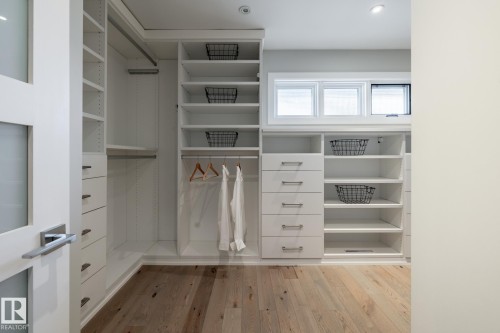 Custom closet system featuring extensive shelving, built-in drawers with modern pulls, and hanging rods - 4204 Aspen Drive E, Edmonton, AB - Indoor