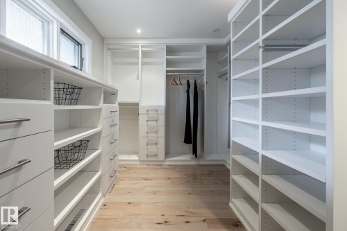Custom closet system featuring extensive shelving, built-in drawers with brushed nickel pulls, and dedicated hanging space - 4204 Aspen Drive E, Edmonton, AB - Indoor With Storage