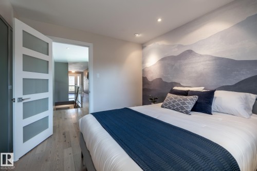 Bedroom featuring a decorative accent wall, light wood-finish flooring, recessed lighting, and a five-panel interior door with frosted glass inserts - 4204 Aspen Drive E, Edmonton, AB - Indoor Photo Showing Bedroom