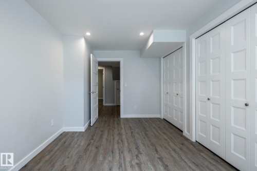 Room featuring wood-finish flooring, two sets of bi-fold closet doors with square paneling, recessed lighting, and light gray wall paint - 4204 Aspen Drive E, Edmonton, AB - Indoor Photo Showing Other Room