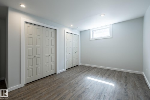 Spacious room featuring wood-finish flooring, two sets of paneled bi-fold closet doors, recessed ceiling lighting, and a single transom window - 4204 Aspen Drive E, Edmonton, AB - Indoor Photo Showing Other Room
