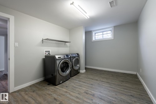 Dedicated laundry area featuring wood-finish flooring, a built-in drying rack, and a high-efficiency washer and dryer set - 4204 Aspen Drive E, Edmonton, AB - Indoor Photo Showing Laundry Room