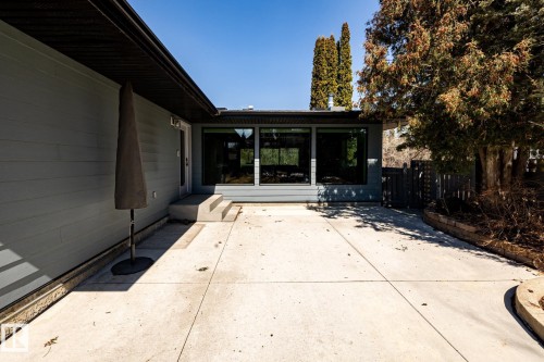 Expansive concrete patio with direct exterior access, featuring a grey siding facade and a dark-framed window wall - 4204 Aspen Drive E, Edmonton, AB - Outdoor