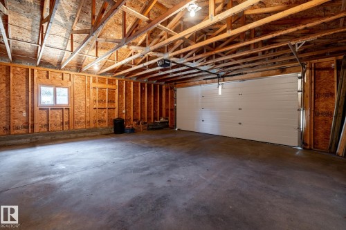 Spacious garage featuring a concrete floor, exposed wood framing, and an automatic overhead door - 4204 Aspen Drive E, Edmonton, AB - Indoor Photo Showing Garage