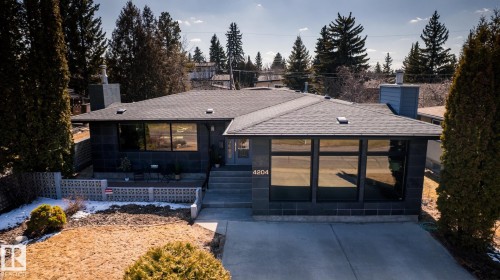 Contemporary residence featuring a dark gray exterior, a shingled roof, and a prominent front entrance with wide concrete steps - 4204 Aspen Drive E, Edmonton, AB - Outdoor
