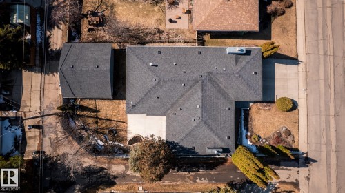 Residential property featuring a dark-toned shingle roof, a detached garage, established front yard landscaping, a concrete driveway, and a paved street frontage - 4204 Aspen Drive E, Edmonton, AB - 