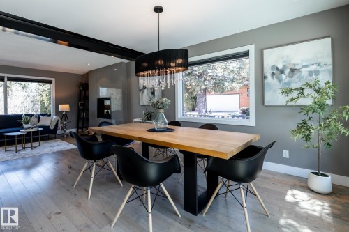 Open-concept dining area featuring wood-finish flooring, a modern chandelier with crystal accents, and a large window - 4204 Aspen Drive E, Edmonton, AB - Indoor Photo Showing Dining Room