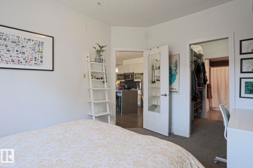 Bedroom space with carpeted flooring, a white interior door, and an open doorway revealing wood-finish flooring - 202 10030 83 Avenue, Edmonton, AB - Indoor Photo Showing Bedroom