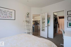 Bedroom space with carpeted flooring, a white interior door, and an open doorway revealing wood-finish flooring - 