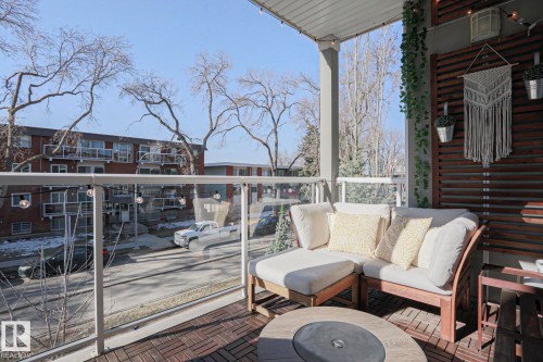 Private balcony featuring glass railings, wood-look floor tiles, and a slatted wood privacy screen - 202 10030 83 Avenue, Edmonton, AB - Outdoor