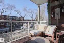 Private balcony featuring glass railings, wood-look floor tiles, and a slatted wood privacy screen - 