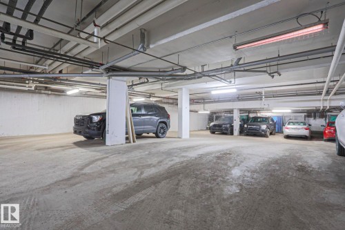 Underground parking facility featuring concrete flooring and a concrete ceiling with exposed utility conduits - 202 10030 83 Avenue, Edmonton, AB - Indoor Photo Showing Garage