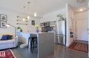 Open-concept kitchen featuring an island with a sink, pendant lighting, stainless steel appliances, and wood-finish flooring - 202 10030 83 Avenue, Edmonton, AB  - Indoor Photo Showing Kitchen 