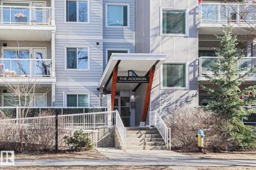 Building entrance featuring a modern awning with wood-finish supports and integrated signage - 202 10030 83 Avenue, Edmonton, AB - Outdoor