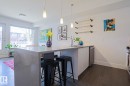 Open-concept kitchen featuring a waterfall island countertop, recessed sink with a high-arc faucet, stainless steel dishwasher, and wood-finish flooring - 202 10030 83 Avenue, Edmonton, AB  - Indoor Photo Showing Kitchen 