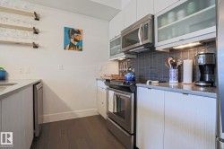 Contemporary kitchen featuring stainless steel appliances, dark wood-finish flooring, and light-toned cabinetry - 