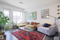 Spacious living area featuring dark wood-finish flooring, a large window, a glass-paneled door, and a square flush-mount ceiling light - 