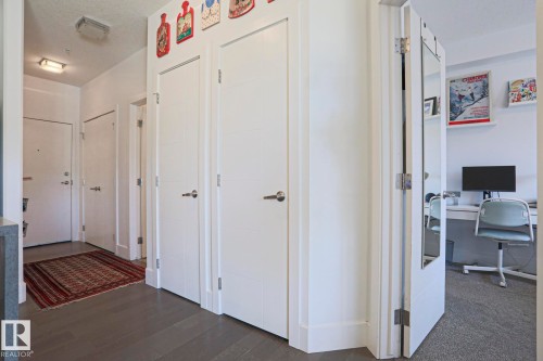 Entryway featuring modern white doors, dark wood-finish flooring, and recessed lighting - 202 10030 83 Avenue, Edmonton, AB - Indoor