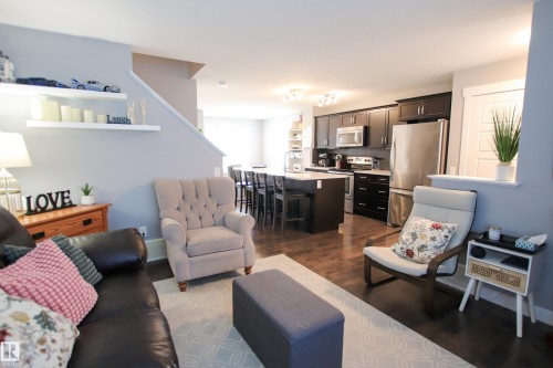 Open-concept living space featuring wood-finish flooring, a contemporary kitchen with dark cabinetry, stainless steel appliances, and an island with seating - 3805 170A Avenue, Edmonton, AB - Indoor Photo Showing Living Room
