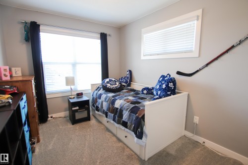 Bright room featuring a large window with blinds and dark curtains, neutral gray wall paint, and gray carpet flooring - 3805 170A Avenue, Edmonton, AB - Indoor Photo Showing Bedroom