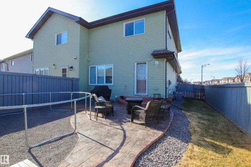 Rear exterior featuring light green siding and a stamped concrete patio - 3805 170A Avenue, Edmonton, AB - Outdoor With Exterior