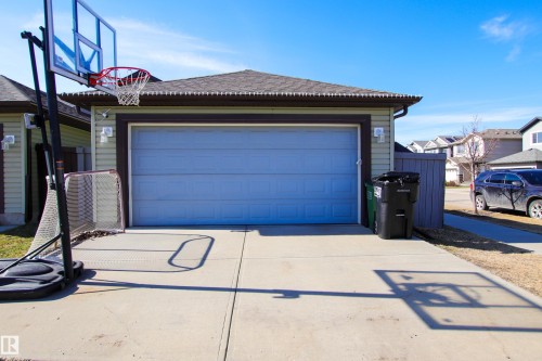 Detached garage with light blue door, concrete driveway, and light green siding - 3805 170A Avenue, Edmonton, AB - Outdoor