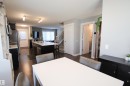 Open concept living area featuring dark wood-finish flooring, a kitchen island with a sink and white countertop, and a contemporary staircase with white risers and dark treads - 3805 170A Avenue, Edmonton, AB  - Indoor 