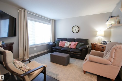 Inviting living area featuring dark wood-finish flooring, a large window with blinds and drapes, and light gray wall paint - 3805 170A Avenue, Edmonton, AB - Indoor Photo Showing Living Room