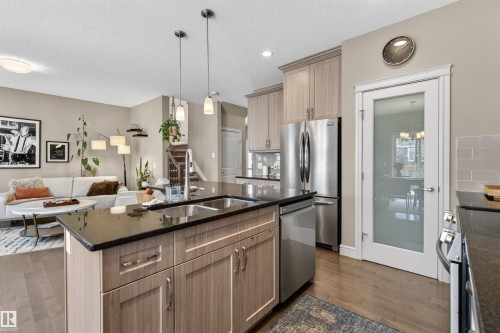 Kitchen island featuring a double-basin sink, black countertop, and light wood-finish cabinetry - 2313 Sparrow Crescent, Edmonton, AB - Indoor Photo Showing Kitchen With Double Sink With Upgraded Kitchen