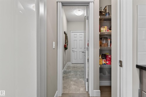 Hallway with tiled flooring and recessed lighting, featuring a pantry with wire shelving and a paneled interior door - 2313 Sparrow Crescent, Edmonton, AB - Indoor Photo Showing Other Room