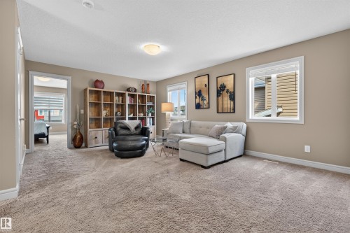 Spacious carpeted room featuring multiple windows with white trim, a built-in recessed light fixture, and a neutral wall color - 2313 Sparrow Crescent, Edmonton, AB - Indoor