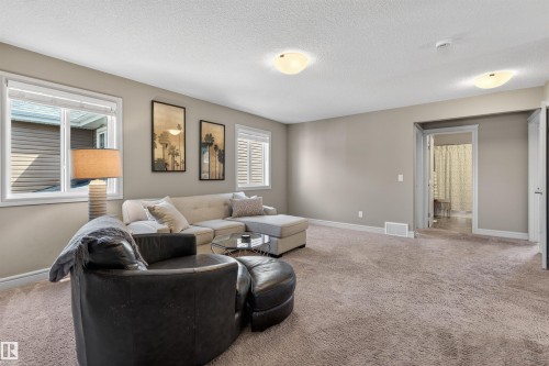 Carpeted room featuring neutral wall tones, multiple windows with white trim, and white ceiling fixtures - 2313 Sparrow Crescent, Edmonton, AB - Indoor Photo Showing Living Room