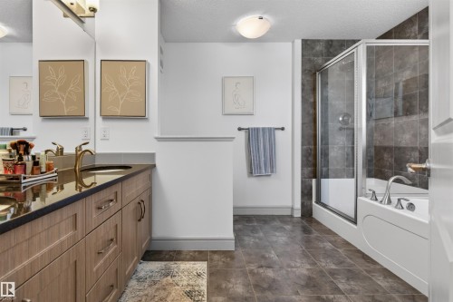 Contemporary bathroom featuring a double vanity with wood-finish cabinetry, dark countertop, and brass-tone fixtures - 2313 Sparrow Crescent, Edmonton, AB - Indoor Photo Showing Bathroom