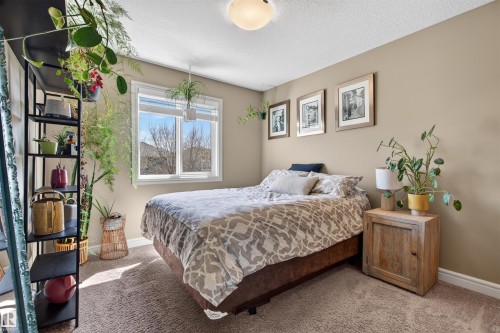 Bedroom featuring light beige wall paint, textured carpet flooring, and a large window with white trim - 2313 Sparrow Crescent, Edmonton, AB - Indoor Photo Showing Bedroom