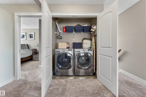 Recessed laundry closet featuring a built-in wire shelf, washer, and dryer units, with a tile-finish floor - 2313 Sparrow Crescent, Edmonton, AB - Indoor Photo Showing Laundry Room