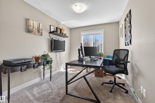 Versatile room featuring neutral wall tones, textured carpet flooring, and a large window providing natural light - 2313 Sparrow Crescent, Edmonton, AB - Indoor Photo Showing Office