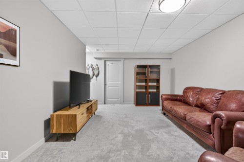 Spacious interior featuring light gray wall paint, light gray carpeting, a drop ceiling, and a white interior door - 2313 Sparrow Crescent, Edmonton, AB - Indoor