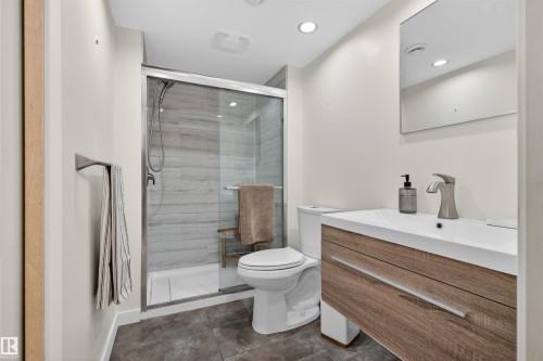 Contemporary bathroom featuring a glass-enclosed shower with horizontal tile, a floating wood-finish vanity with an integrated sink, and recessed lighting - 2313 Sparrow Crescent, Edmonton, AB - Indoor Photo Showing Bathroom